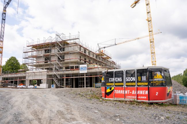 Außenansicht des Rohbaus des Hotels Schutzhütte mit einer roten Gondel